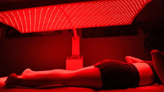 Patient receiving red and near-infrared light therapy under LED panel