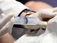 Doctor administering a close-up ozone prolotherapy injection with a syringe to repair a damaged or inflamed joint.