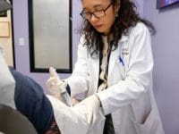 AMA Regenerative Medicine doctor in a white coat administering an ozone injection to a patient's elbow.