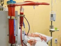 The full EBOO machine in operation, showing blood circulating through the filter while a patient rests in the background.