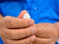 Close-up of a man's hands, wearing a blue shirt, gently holding a single, small vial containing regenerative stem cells.