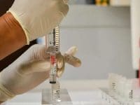 A close-up view of a professional loading a vial of mesenchymal stem cells into a syringe for precise regenerative medicine treatment.