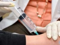 Medical professional administering a regenerative ozone injection into a patient's ankle joint.