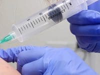 Close-up of a medical professional administering an ozone injection into a female patient's shoulder for pain relief.