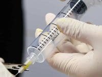 Close-up view of the sterile syringe tip during an ozone injection procedure on the elbow.