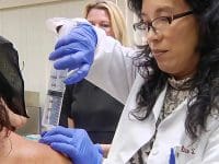 Dr. Alice Pien performs a shoulder ozone injection using a large syringe to treat a damaged joint in her patient.