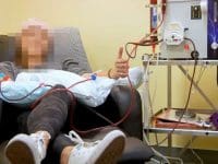 Full view of a vaccine-injured patient giving a thumbs-up while receiving EBOO ozone blood treatment.